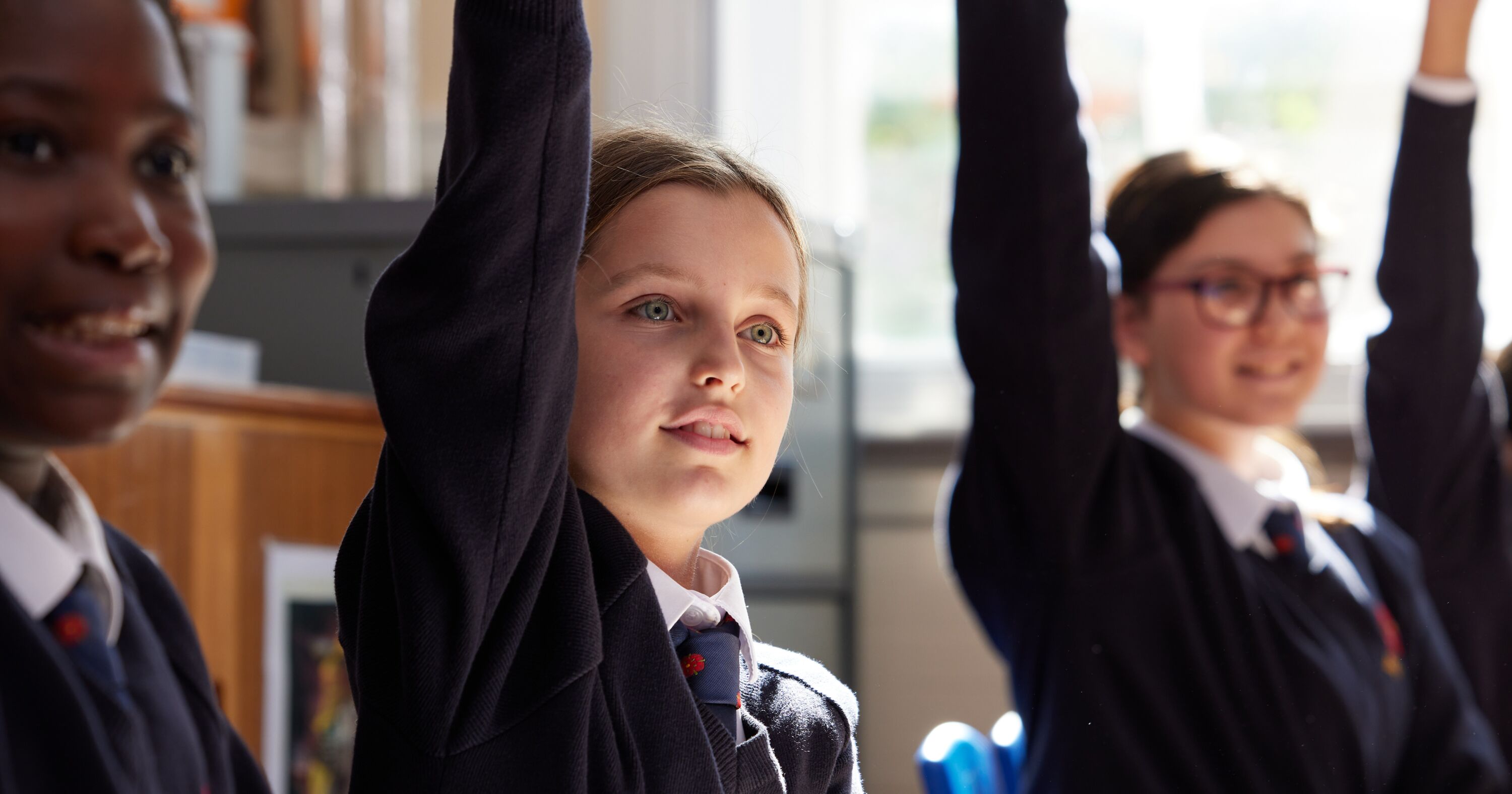 Students with arms raised in answer to a question